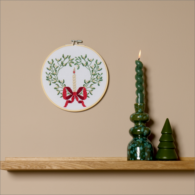Gestickter Weihnachtskranz mit Kerze im Stickrahmen als Wanddekoration.