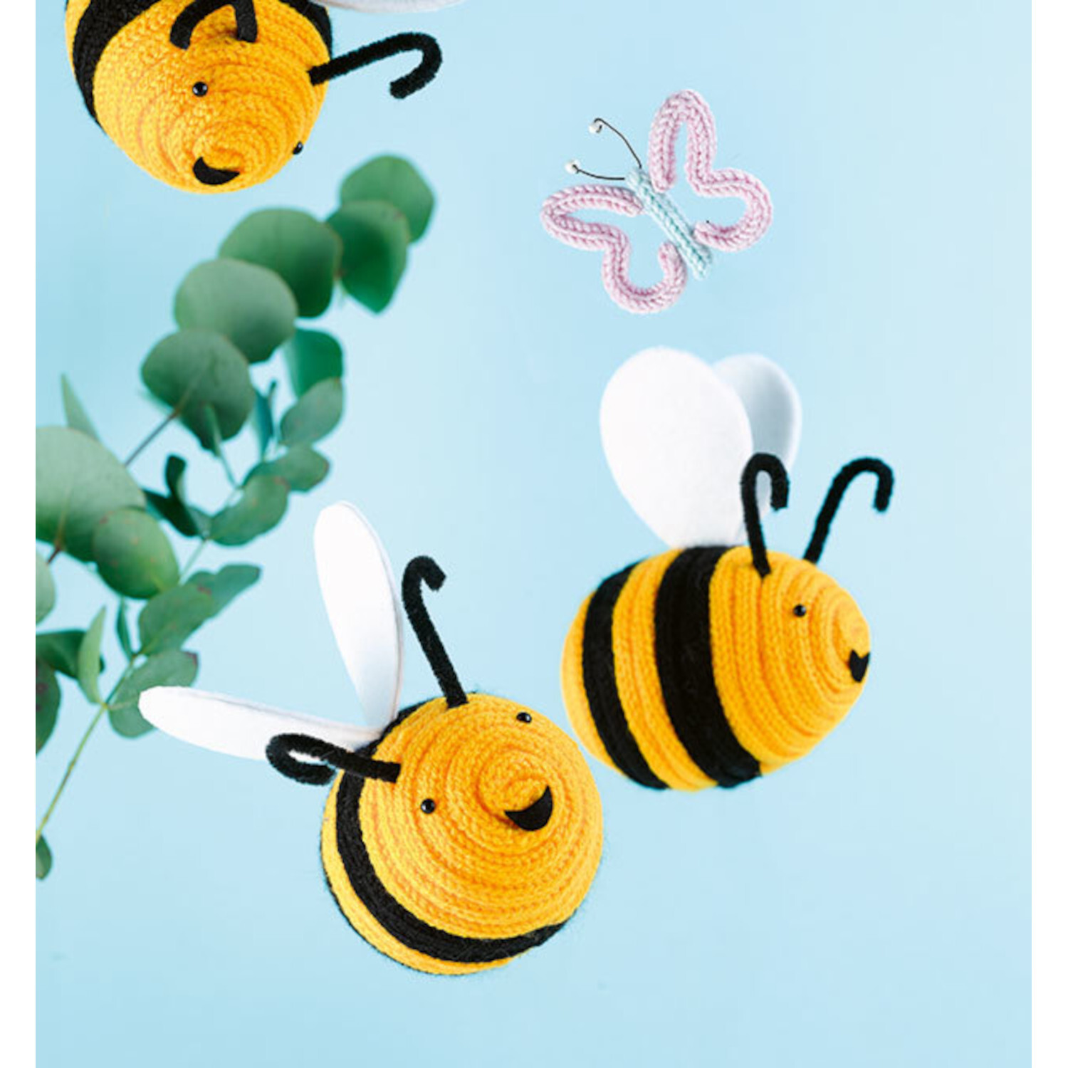 Kreativ kinderleicht Strickliesel: Gelbe und schwarze gestrickte Bienen mit weißen Flügeln vor blauem Hintergrund.