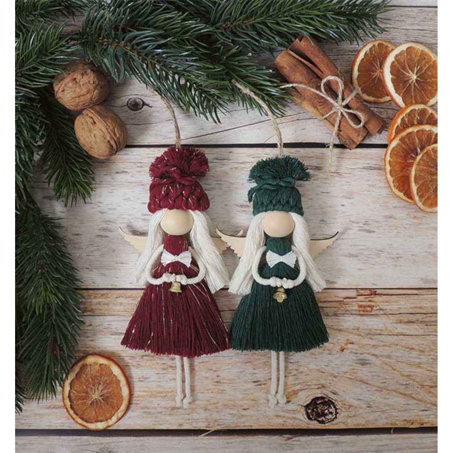 Märchenhafte Makramee Engel: Zwei Engel aus Makramee in Rot und Grün, dekoriert mit Tannenzweigen und getrockneten Orangen.