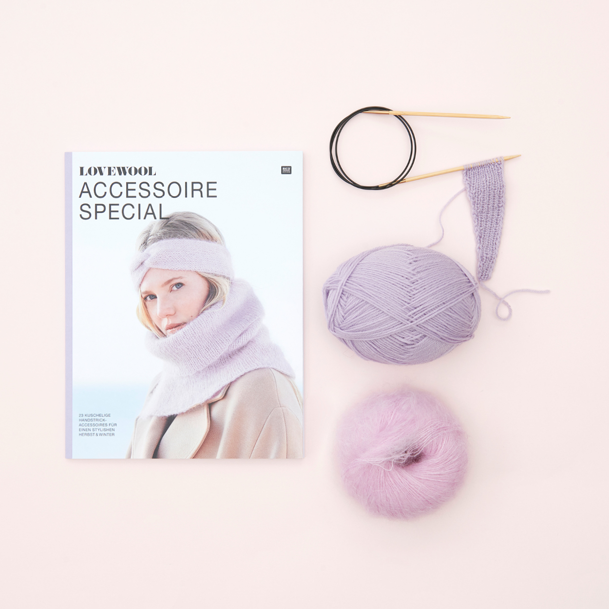 Lovewool Accessoire Special Anleitungsheft mit einem rosa und einem lila garn mit Strickstück und Rundstricknadel. Flatlay von Produkten.