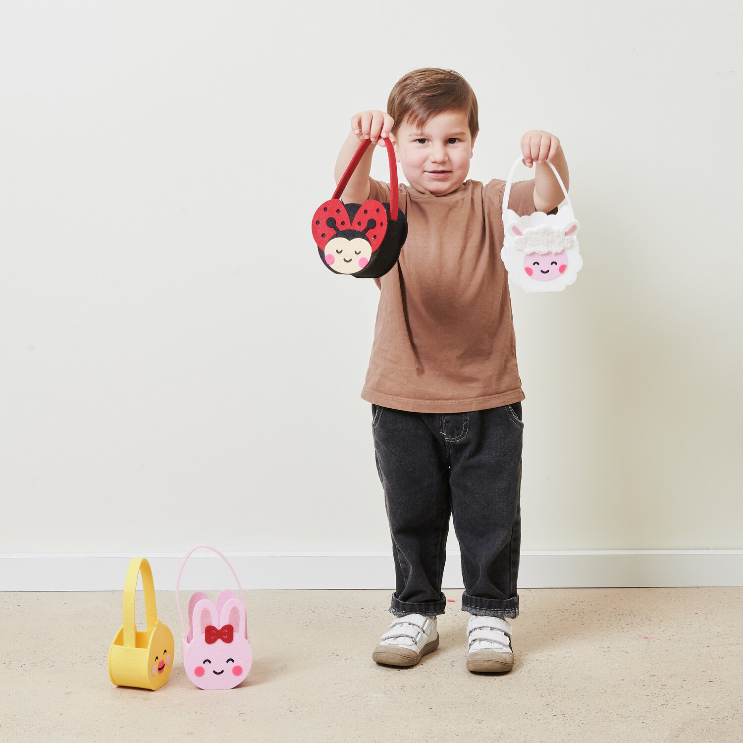 Filz-Korb Marienkäfer: Kind hält zwei Filz-Körbe, Marienkäfer und Lämmchen, von Rico Design.