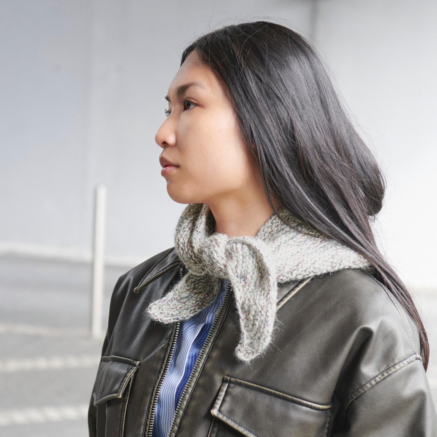 Strickset Mini Dreieckstuch Modell 09b: Frau trägt ein graues Dreieckstuch über einer Jacke. Ideal für stilvolle Akzente im Alltag.