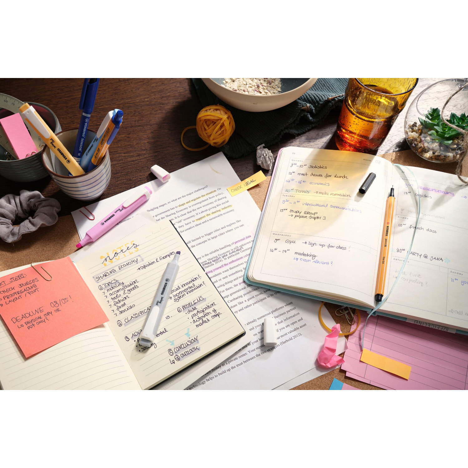 swing cool Textmarker Pastell 4 Stück auf einem Schreibtisch mit Notizbüchern und Schreibutensilien.