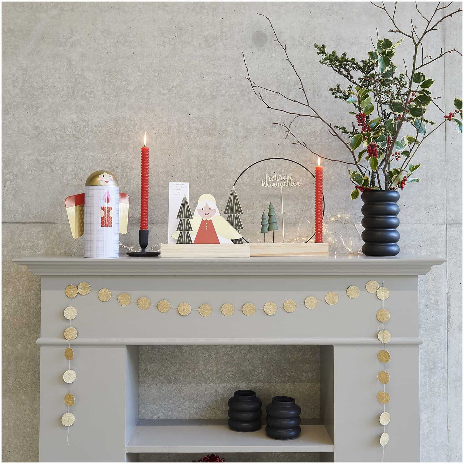 Keramik Vase schwarz von Rico Design auf einem Kaminsims mit roten Kerzen und weihnachtlicher Dekoration.