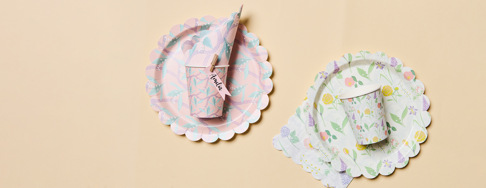 Zwei Pappbecher und Pappteller mit Servietten in jeweils passenden floralen Motiven. Flatlay von Produkten der Kollektion The Sky Is The Limit.