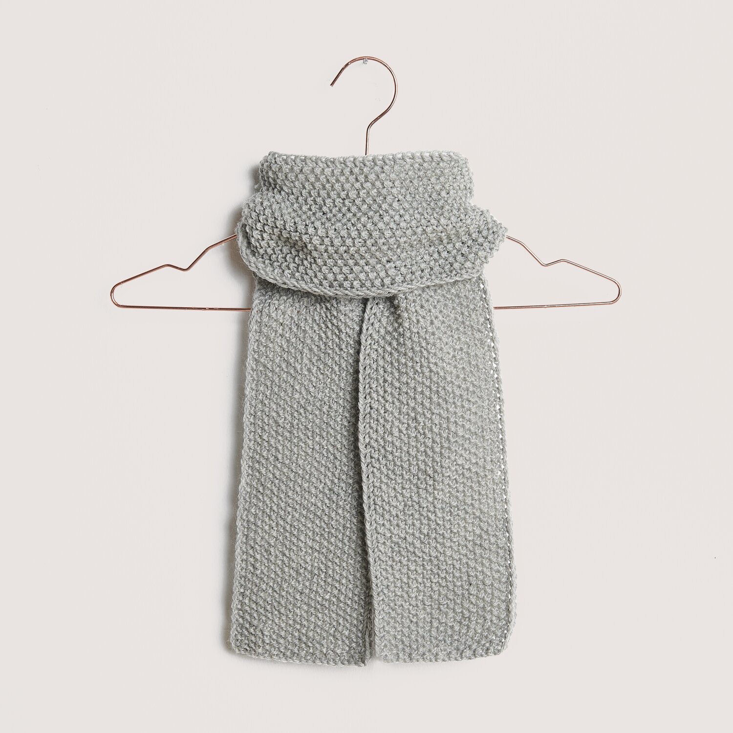 Die Neue Masche No. 14 Winter von idee. Creativmarkt Essentials Soft Merino aran Schal in Hellgrau von Rico Design, gestrickt und auf einem Kleiderbügel präsentiert. Ideal für kalte Tage.