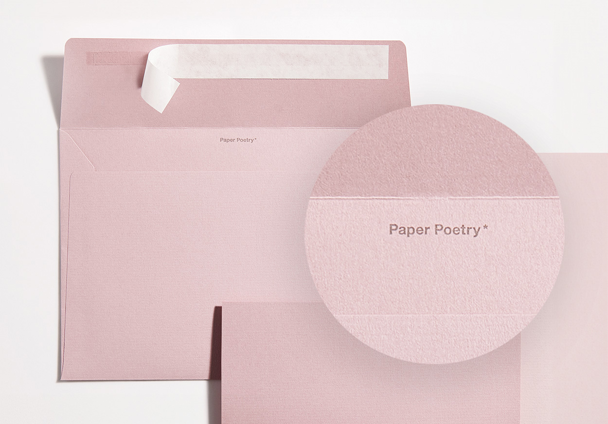 Rosa Umschlag mit passender Karte und Close-Up von Schriftzug im Umschlag. Flatlay von Produkten.
