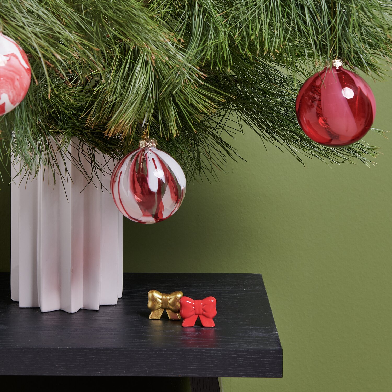 Porzellan Schleife und Glaskugeln in Rot und Weiß schmücken einen Weihnachtsbaum in modernem Design.