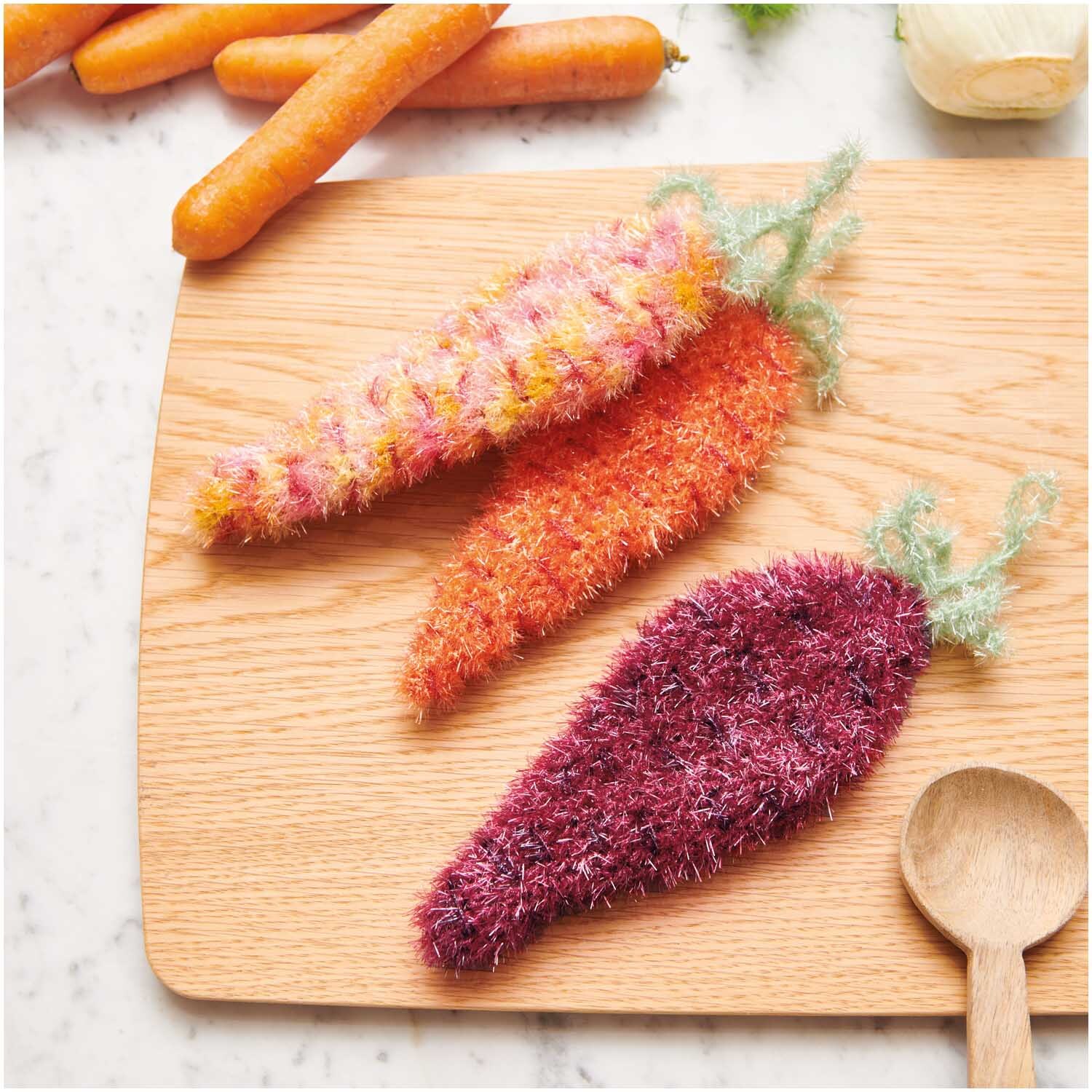 Creative Bubble: Strickgarn von Rico Design in verschiedenen Farben, geformt als Karotten auf einem Holzbrett.