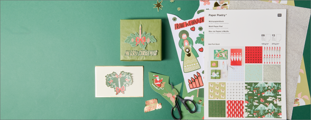 Weihnachtsgeschenke und Karte aus Motivpapierblock auf grünem Hintergrund.