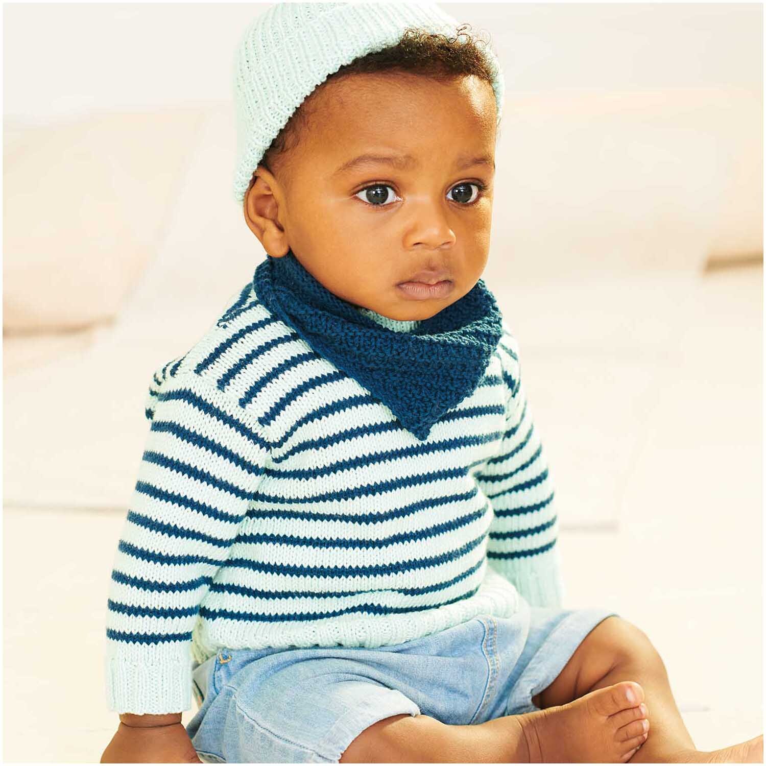 Baby Organic Cotton 50g 150m Farbe Marine von Rico Design Baby Organic Cotton: Ein Baby trägt einen gestreiften Pullover und Mütze aus Bio-Baumwolle in Blau.