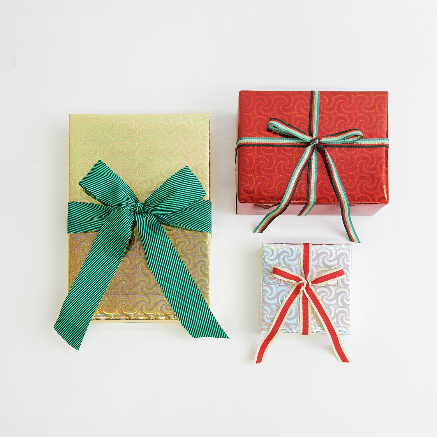 Paper Poetry Webband diagonale Streifen 50mm 3m Farbe Grün von Rico Design Paper Poetry Geschenkpapier Holographisch mit Sternen Mix: Drei Geschenke in Gold, Rot und Silber, verziert mit grünen und roten Bändern.