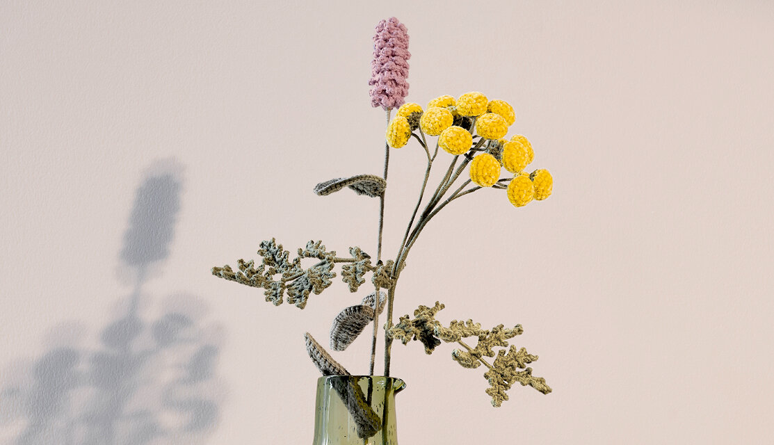 Material Ricorumi In the Meadow Rainfarn zeigt gehäkelte Wiesenblumen in Glasvase mit gelben Blütenbällen, rosa Blume und filigranen grünen Blättern.