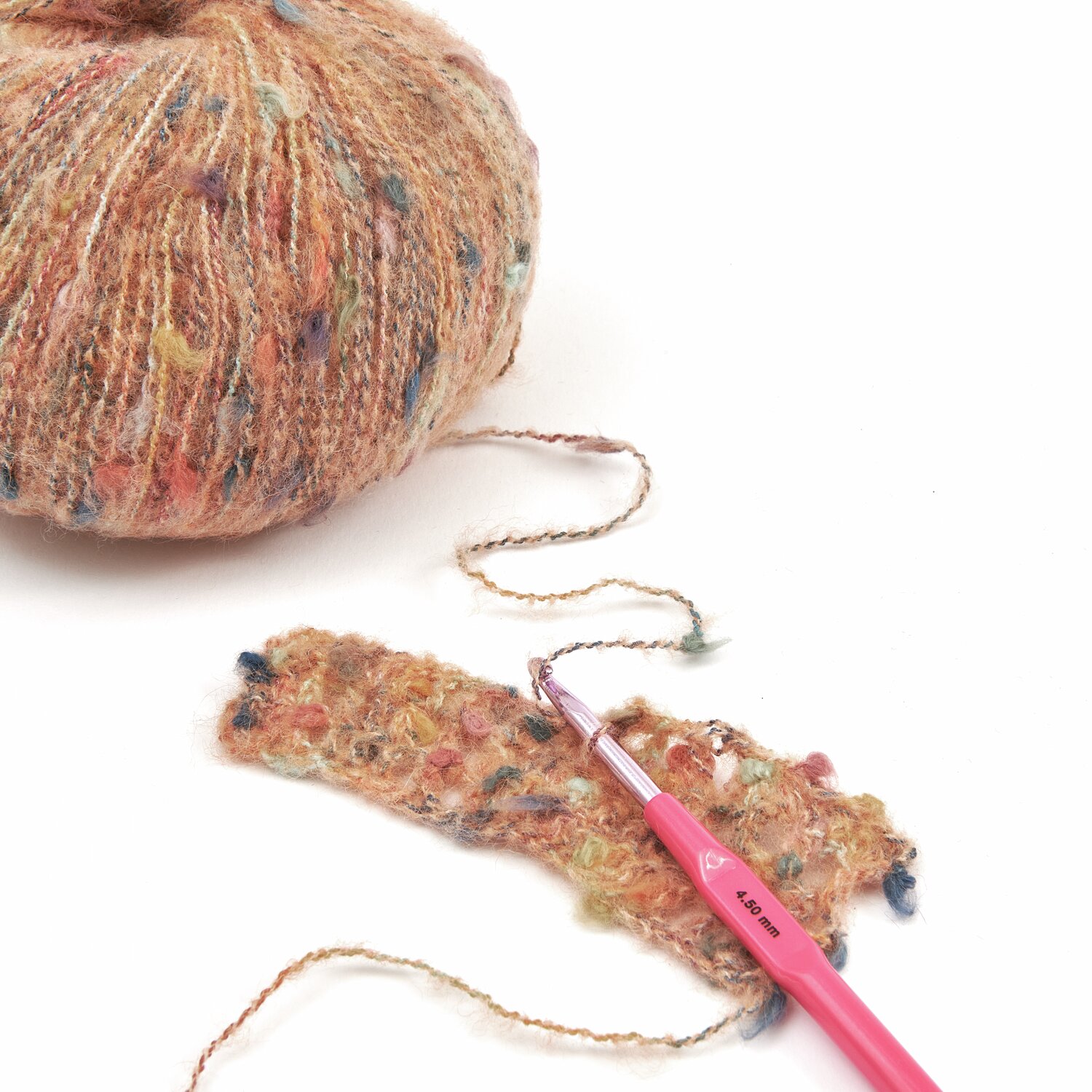 Lovewool No. 21 Herbst-Winter Sprachauswahl deutsch von Rico Design Ein Knäuel mehrfarbiges Garn mit einer gehäkelten Probe und einer rosa Häkelnadel. Ideal für kreative Strickprojekte. Perfekt für Handarbeitsliebhaber, die hochwertige Materialien schätzen.