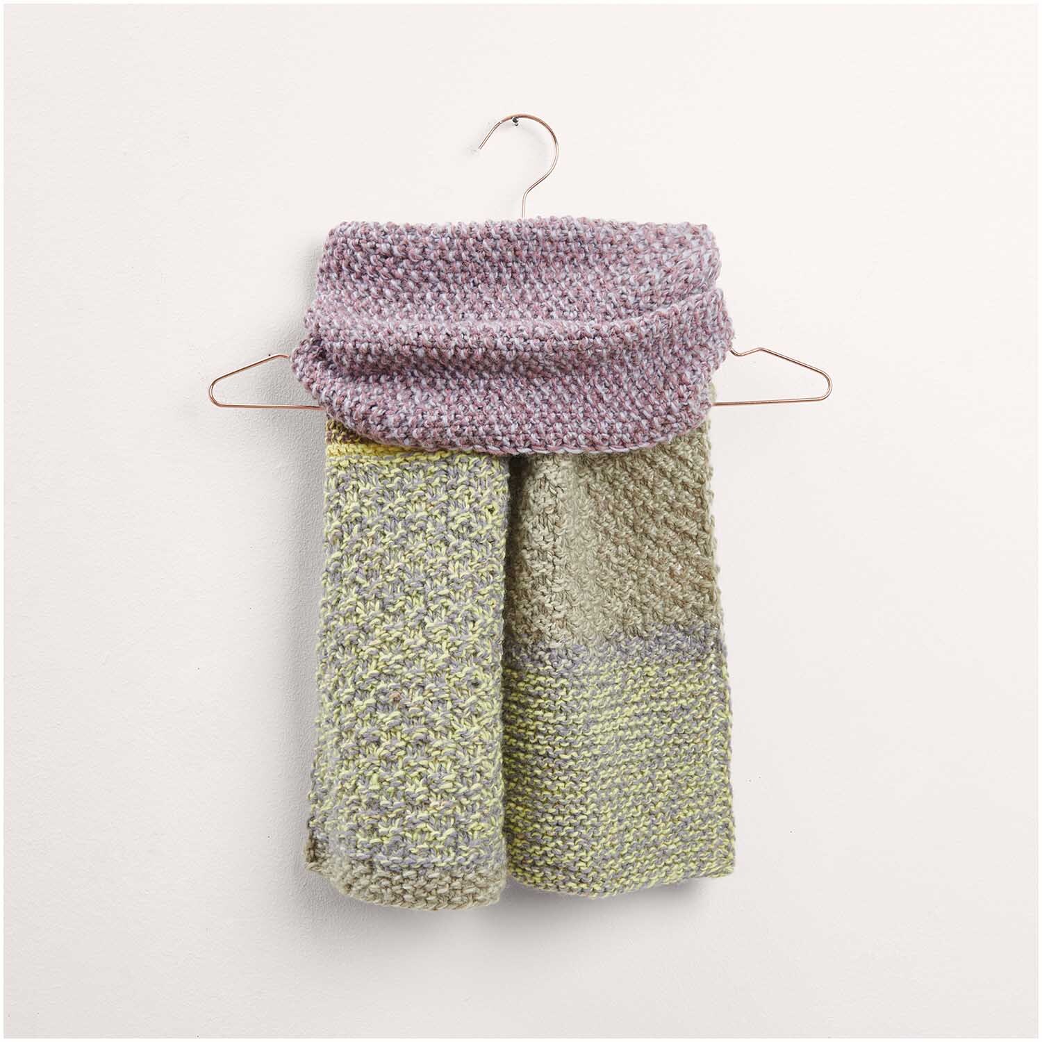 Strickset Schal Modell 31 aus Made by Me Nr. 17 in sanften Lila- und Grüntönen. Der Schal hängt auf einem Kleiderbügel und zeigt die feine Strickstruktur. Ideal für stilvolle Wintermode.